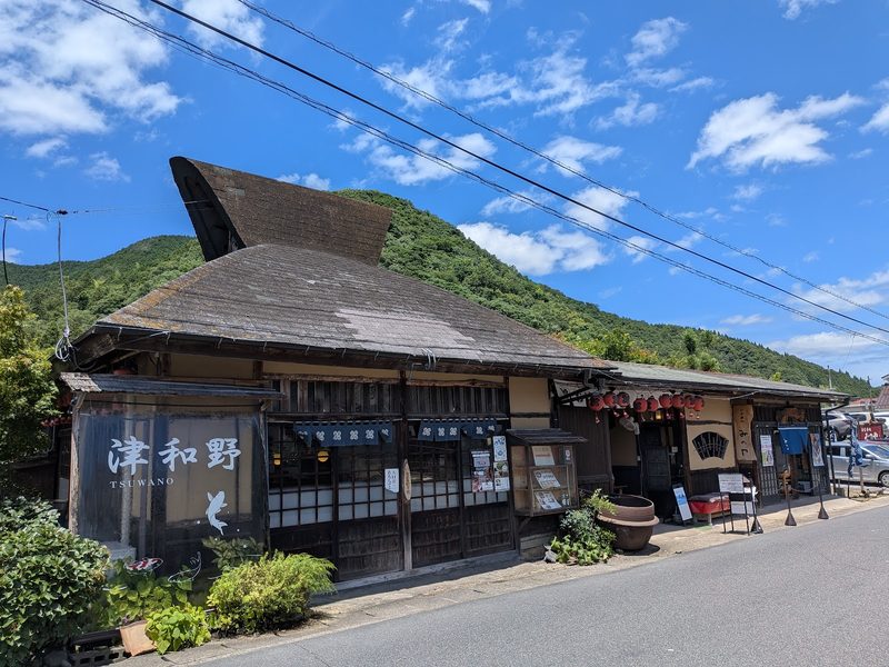 青空の下、山を背にした茅葺き屋根風のみのやの外観